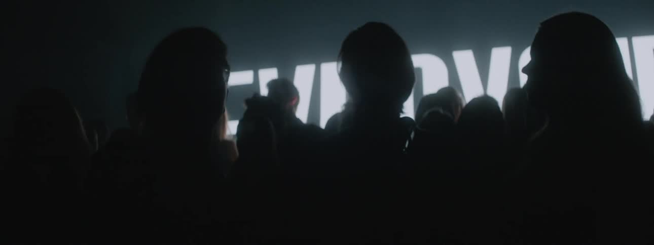 The people stand together in front of the flashing screen