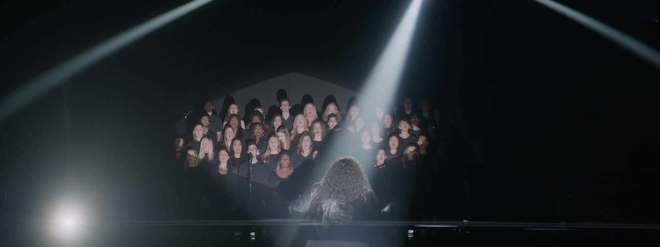 A choir sings in a room with flashing lights