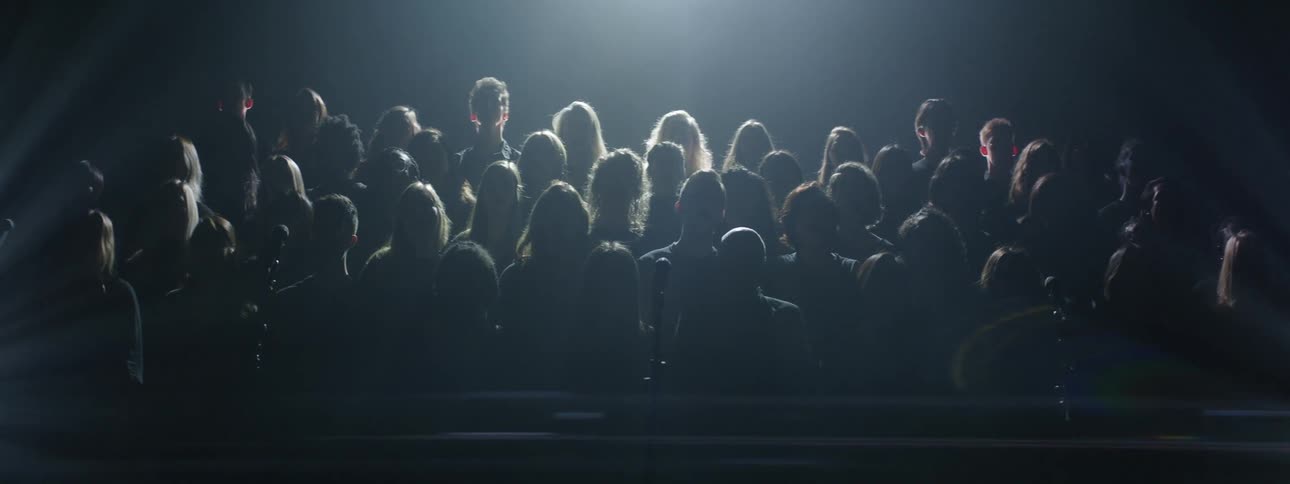 A choir performs in a dark room