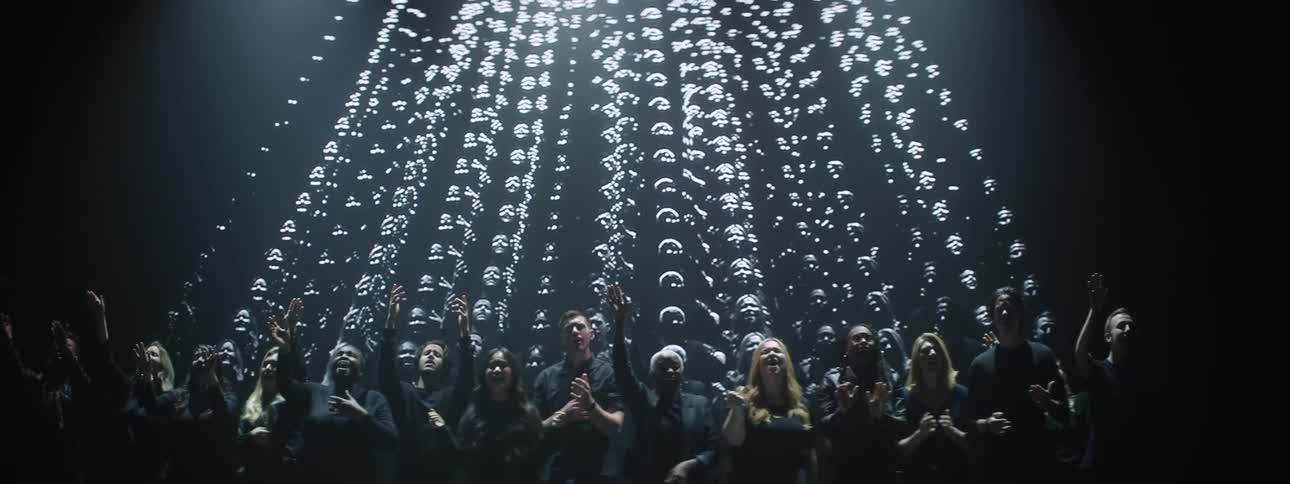 A choir is singing on a stage as an image is projected behind them