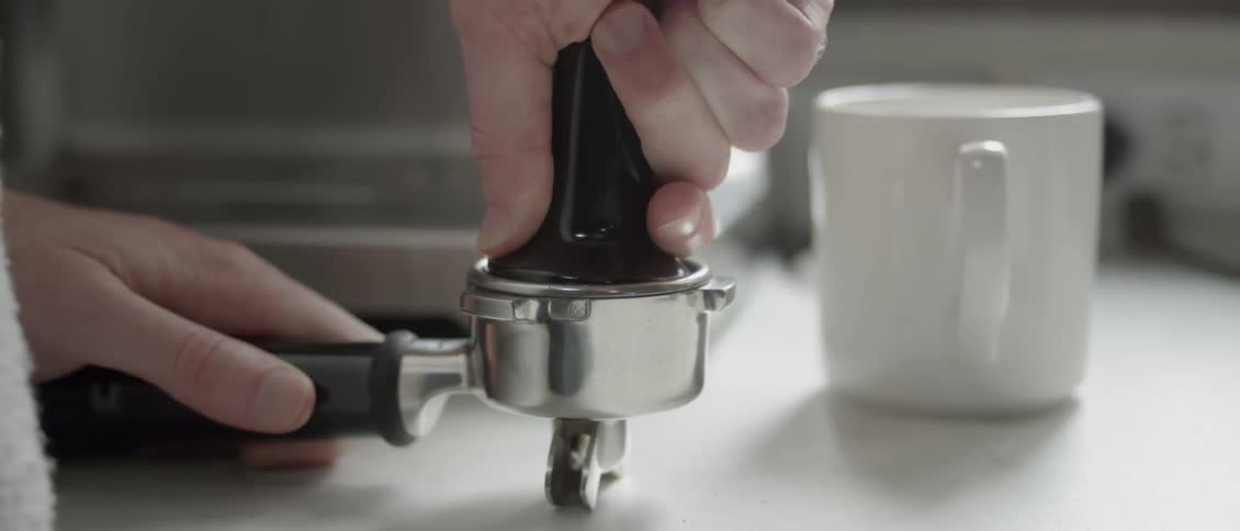 A man presses coffee grounds into a tool