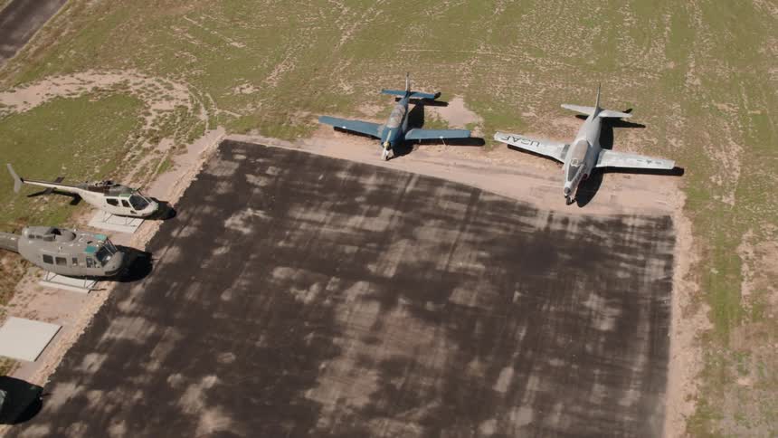 Airplanes and helicopters are parked at a rural airport