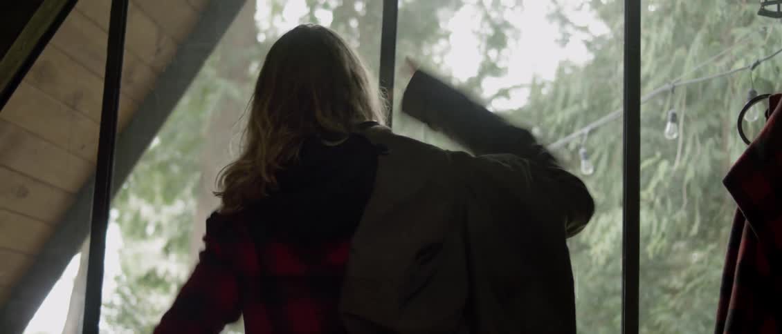 A man with long hair puts on a coat, and walks away
