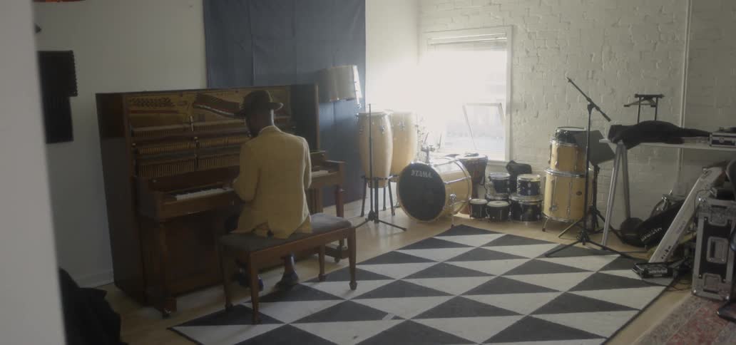 A man is sitting in the music studio playing the piano