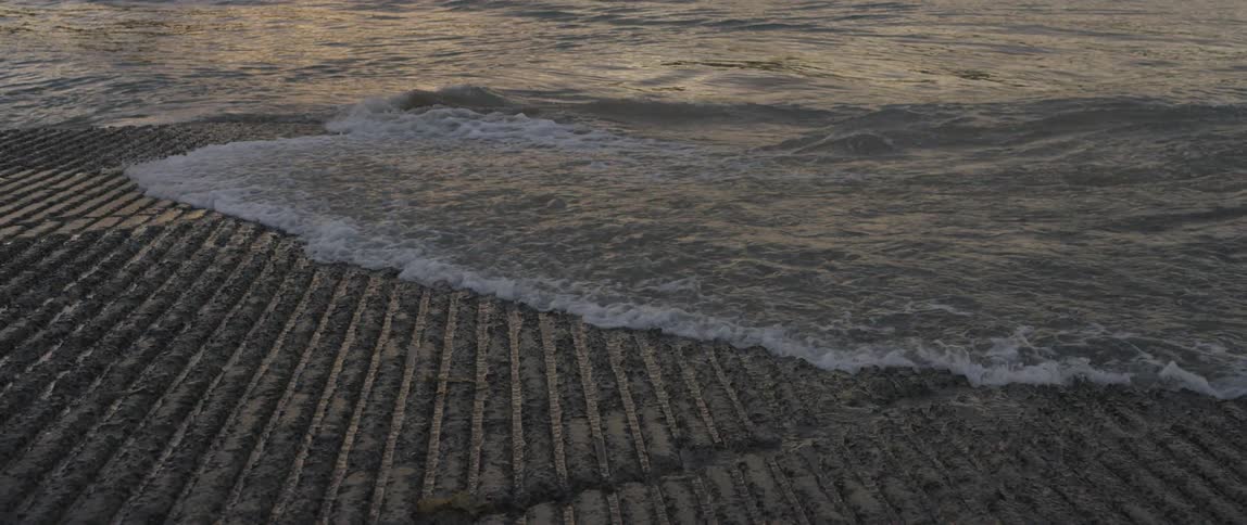 Waves washing on shore and between furrows of mud