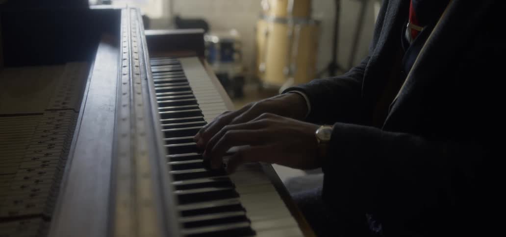 Man wearing suit us playing piano in music room