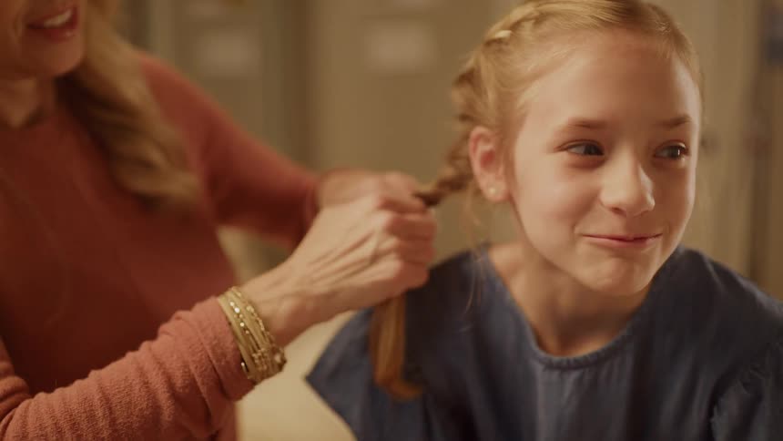 A mom is braiding her daughters hair
