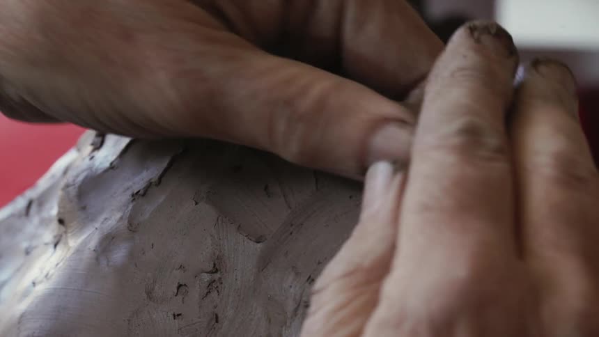 A person is sculpting clay by hand