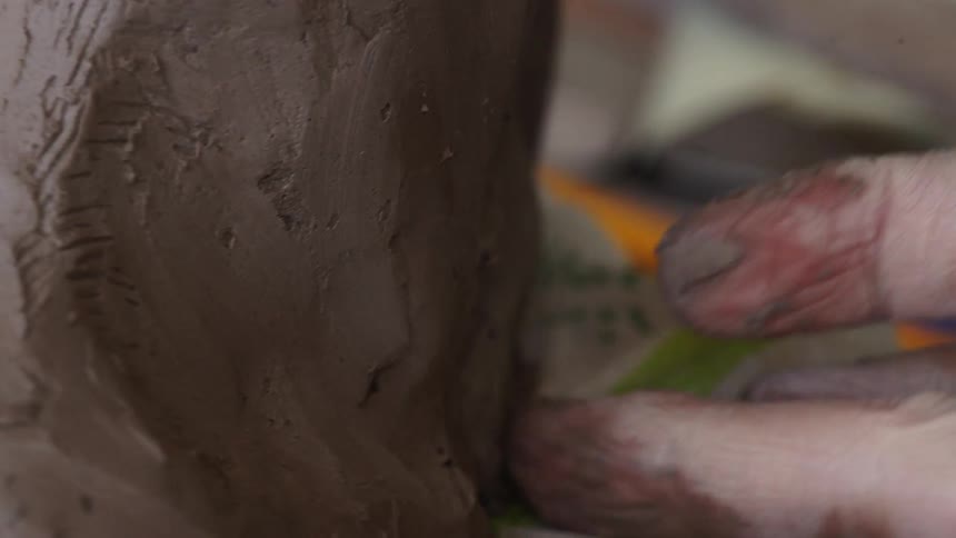 A person presses the clay forming it