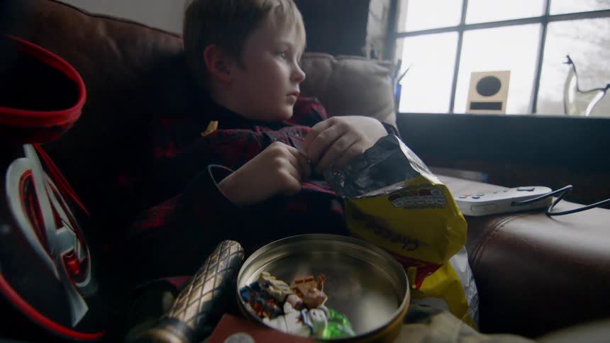 Child sits on a couch surrounded by toys