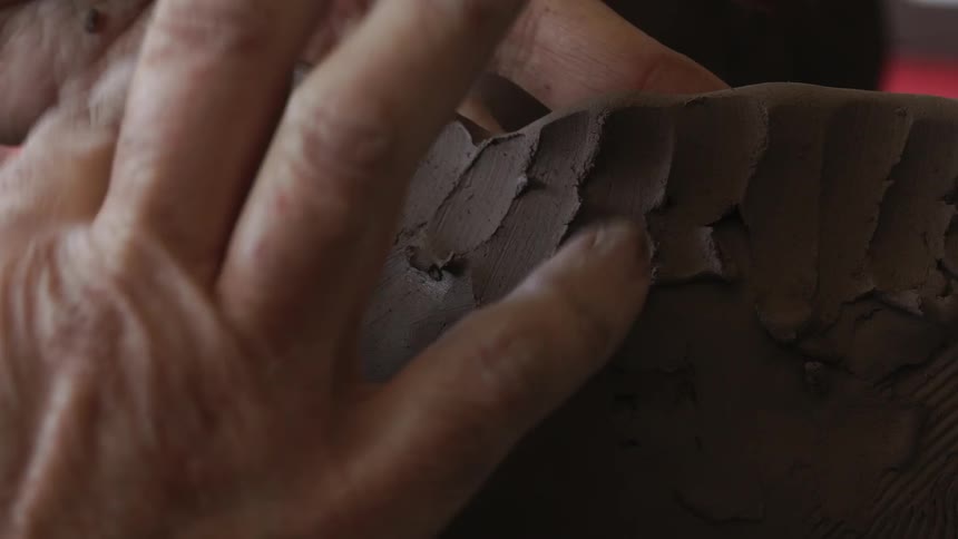 A person forms a clay sculpture