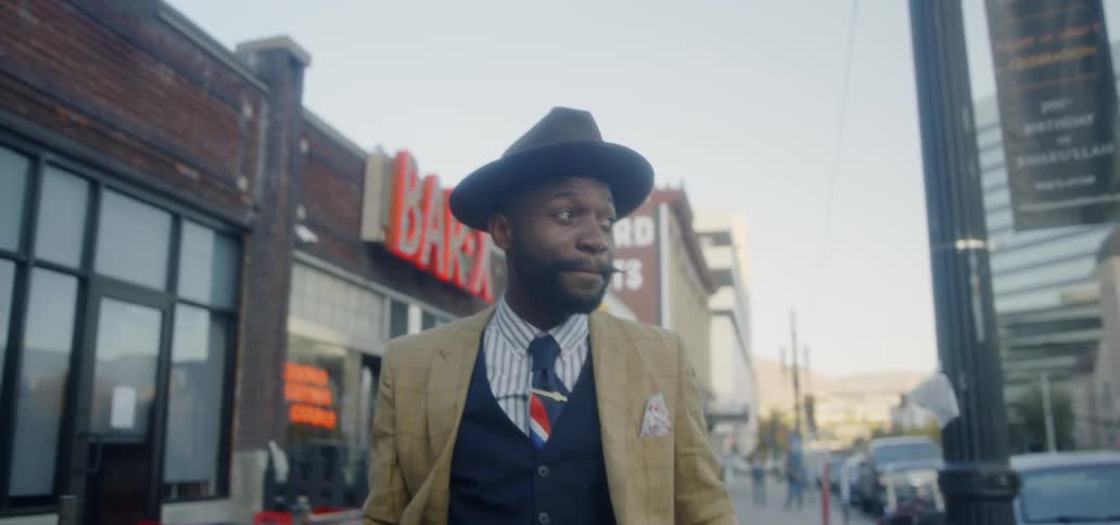 Man in suit is walking down city street during the day