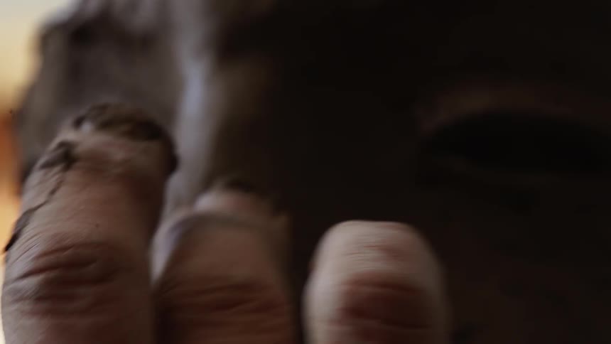 Person sculpting a nose on face made out of clay