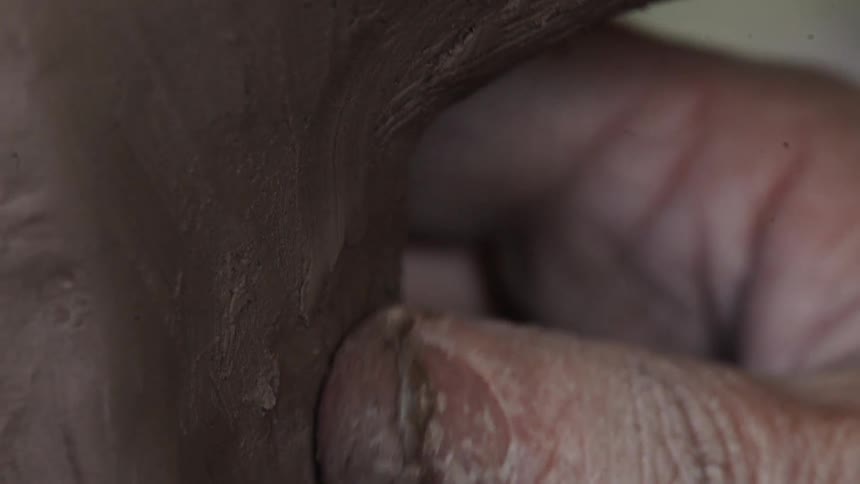 A person forming pottery with their fingers
