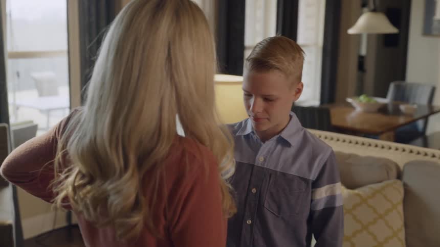 A woman dances with a young boy in a living room