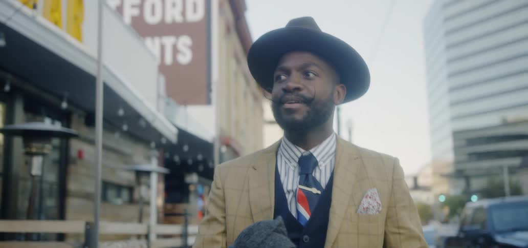 A man is smiling as he walks down the city street