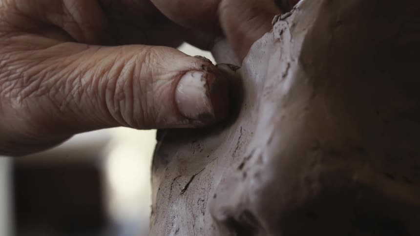 Person is forming a sculpture out of clay
