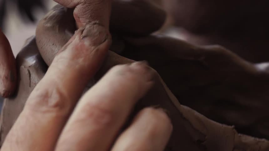 A person is forming some clay slowly with his fingers