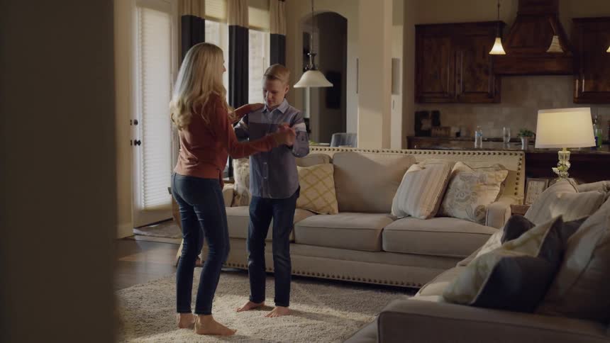 A mom teaches her son to dance in the living room