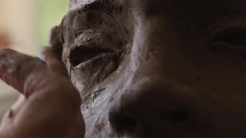 A person is sculpting a head with clay