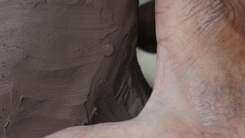 Person smooths a lump of brown clay