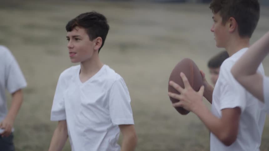 Group of kids in white shirts run on a field