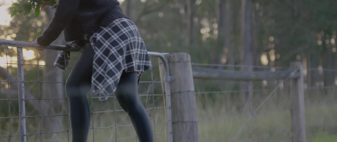 A woman is jumping a fence