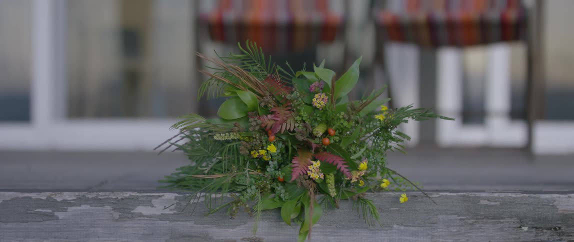 A bouquet of plants and flowers lays on the ground