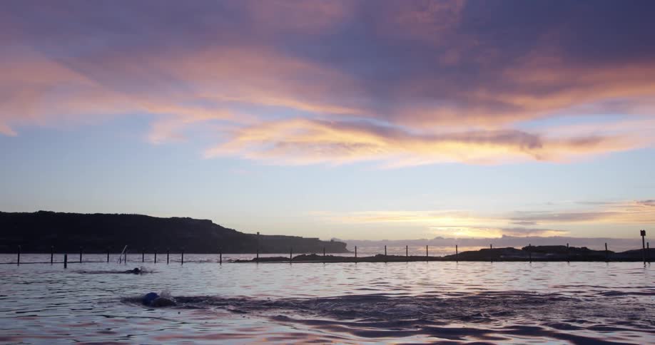 Person swimming in the water at sunset