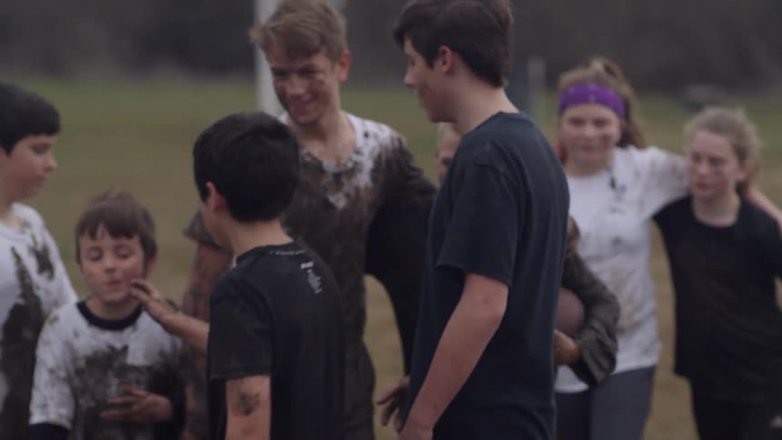 A group of kids shake and hug after playing football
