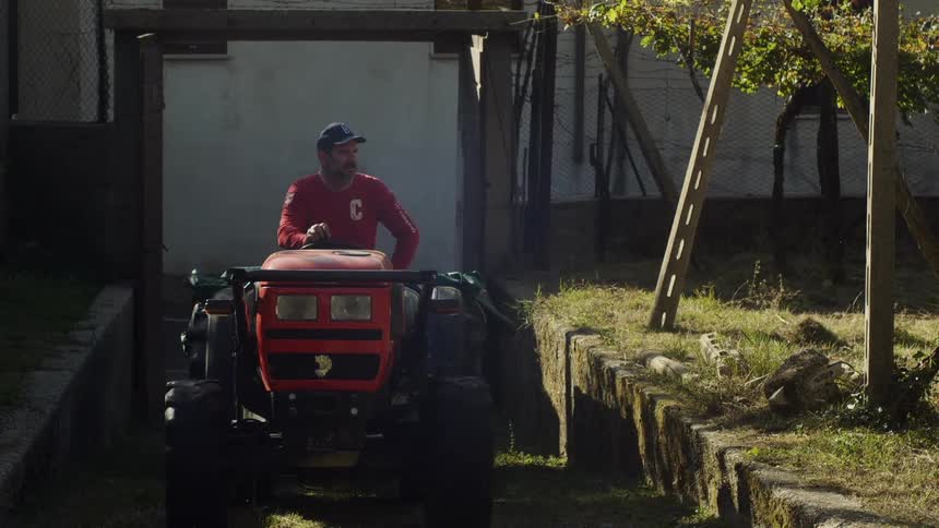 A man rides his tractor up the hill