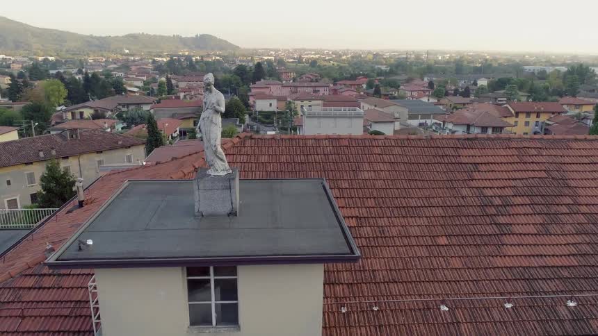 A statue is displayed on top of a building