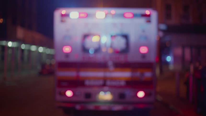 The ambulance is parked on the street with it's lights flashing