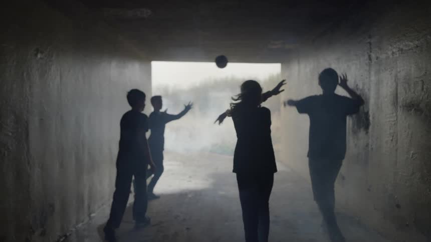 A group of children run down the dark tunnel