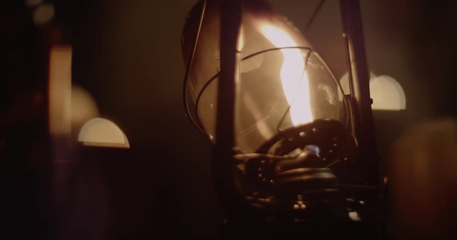 A person is turning up then blowing out the flame inside a lantern