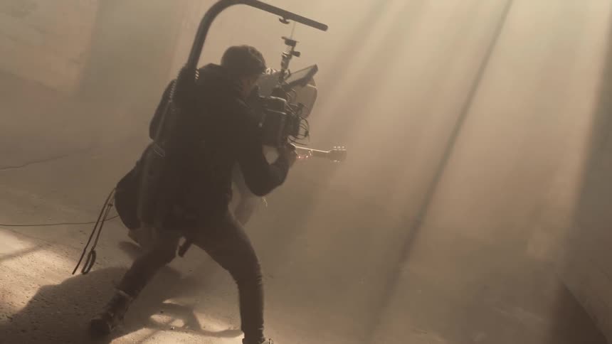 The cameraman is filming a man playing guitar