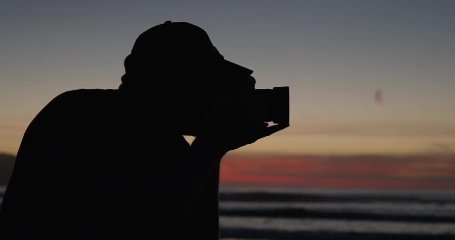 A photographer on the beach at sunset in silhouette