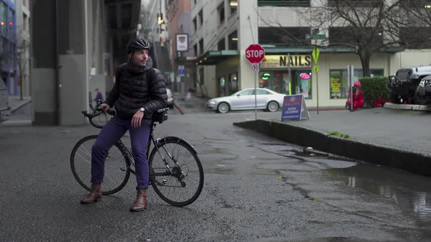 Man is looking around while sitting on bicycle on wet city street