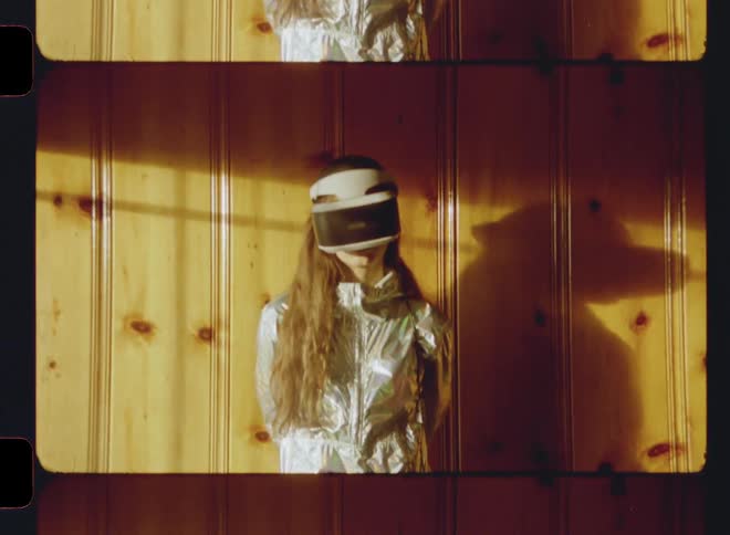 Young girl wears virtual reality headgear as she stands near a wall