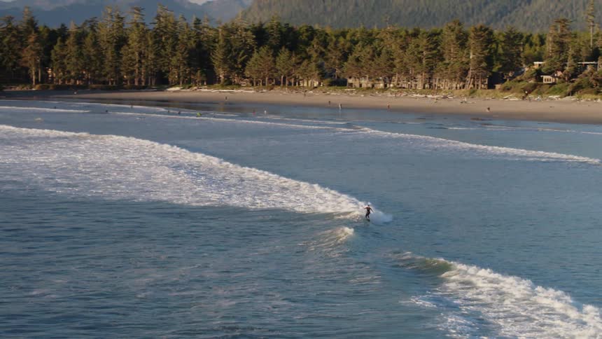 Person surfing in ocean waves on sunny day