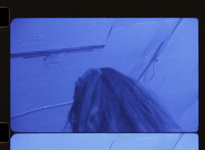 A woman dances around a room while lights flash