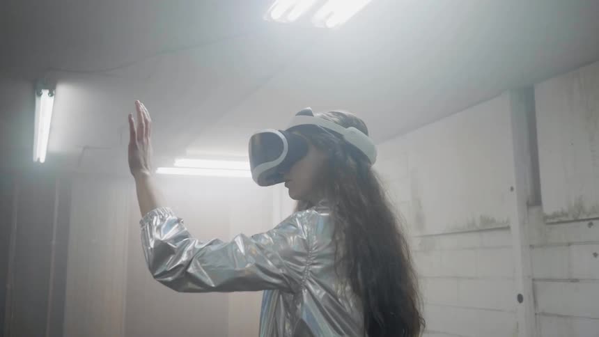 A woman reaches her hand up while wearing a virtual reality headset