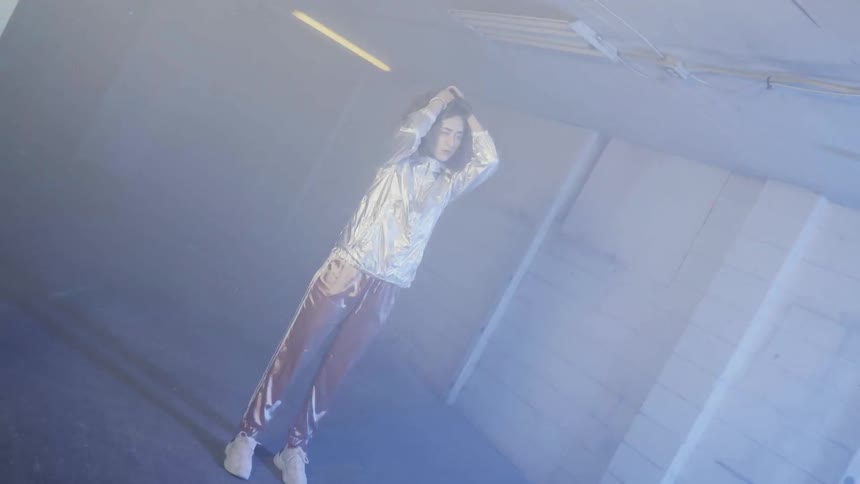 A woman is holding her head as she stands inside an abandoned building amid flashing lights