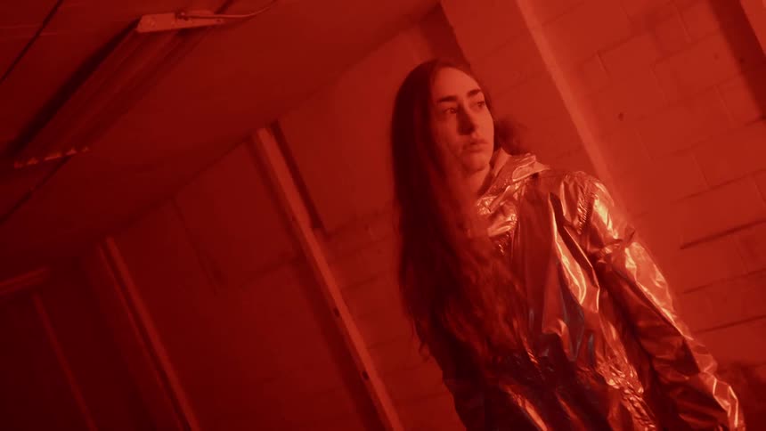A woman stands in a room while lights flash different colors