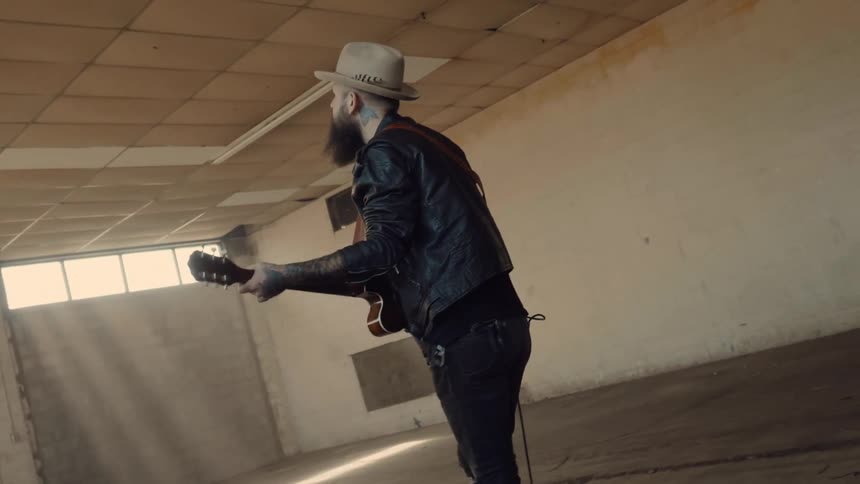 Man playing guitar in a large empty room of a building