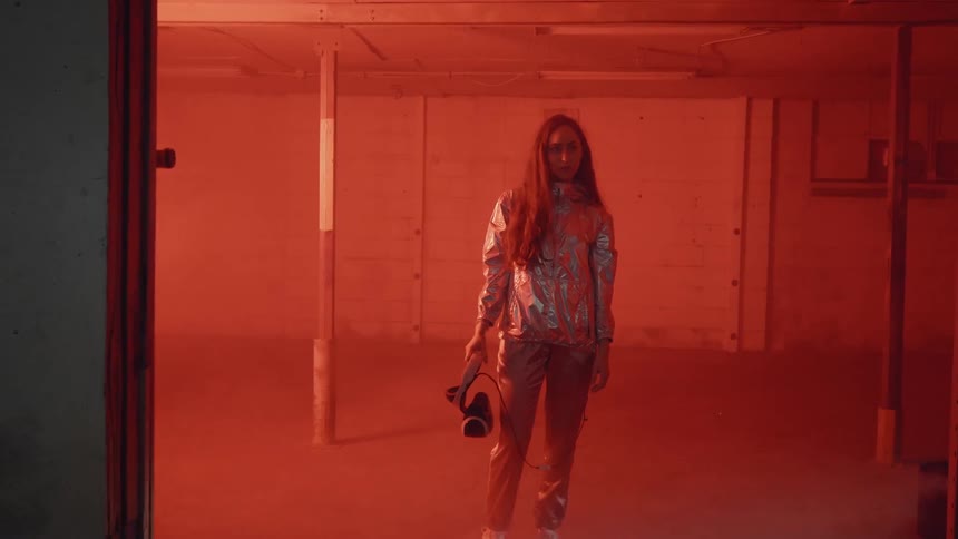 Woman holding virtual reality headset is standing in empty room with flashing lights