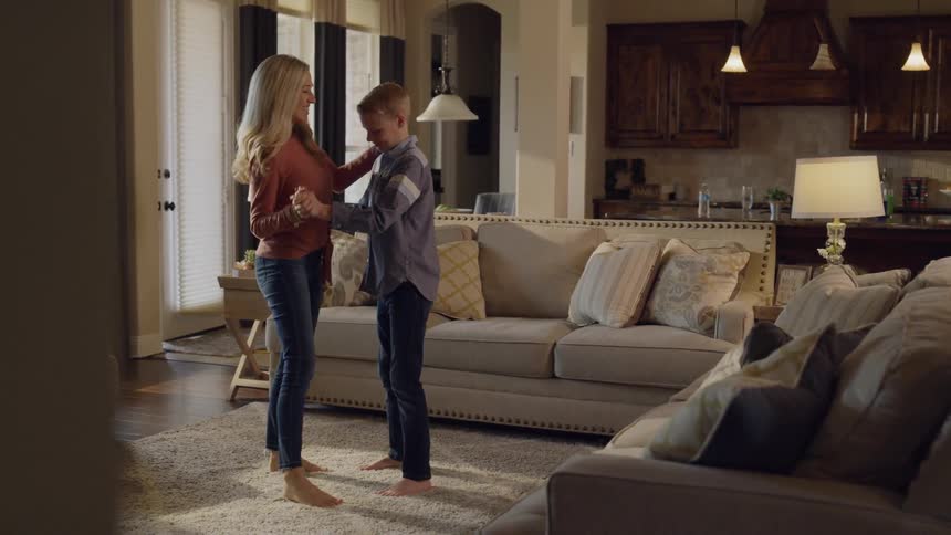 A mother and child dance in the living room