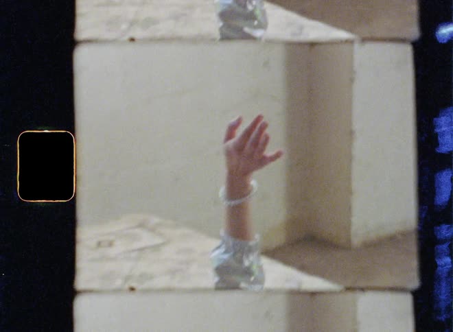 The woman is laying on the bed with a headset waving her hands
