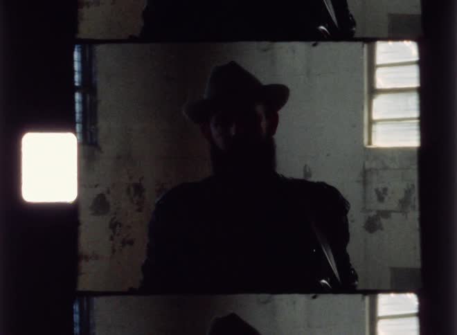 A man with a guitar stands in an empty room