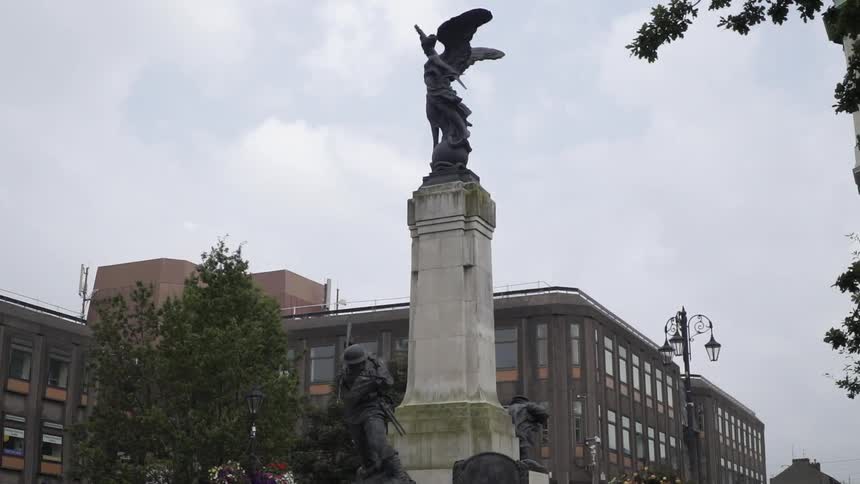 Clouds are hanging in the sky above a war memorial with an angel statue